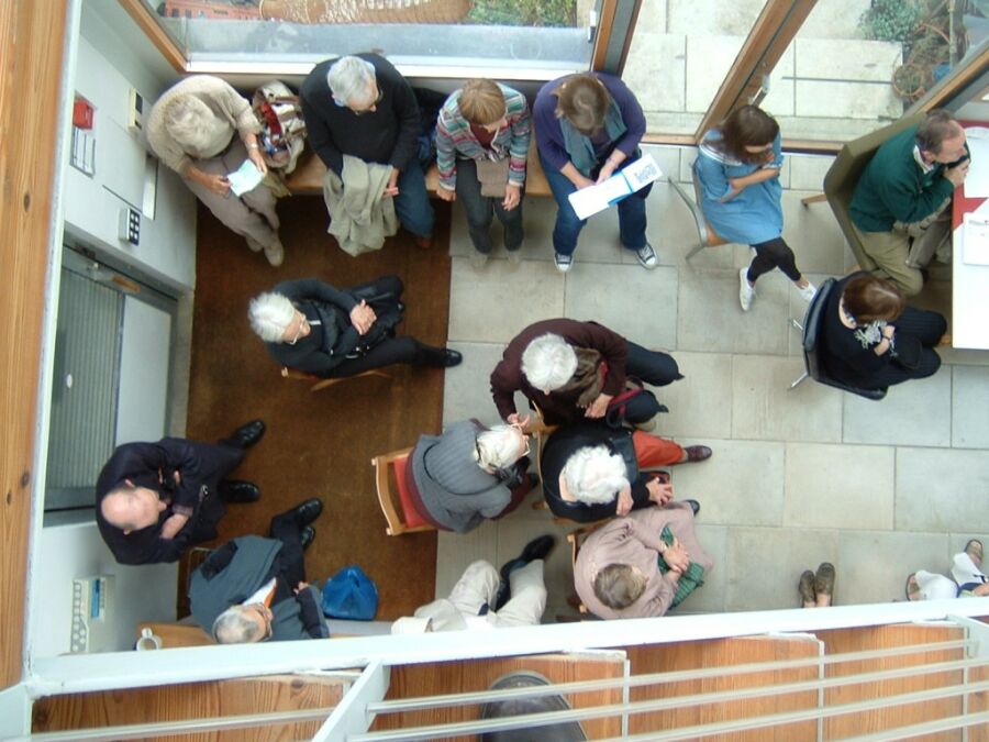 Gathering of audience members viewed from above in atrium for recital.