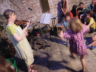 Tenth anniversary party: view of rear courtyard with Nicolette playing violin accompanied by Freda and Luca dancing.