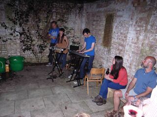 Tenth anniversary party: night view from unit 3 into rear courtyard of Esther and Chris playing.