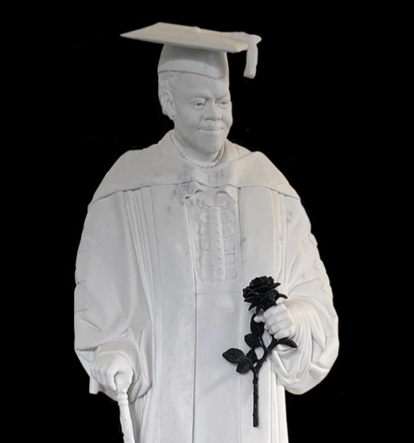 white marble statue of black woman with black rose in academic robe and hat.