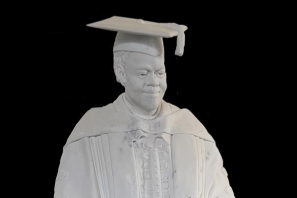 white marble statue of black woman with black rose in academic robe and hat.