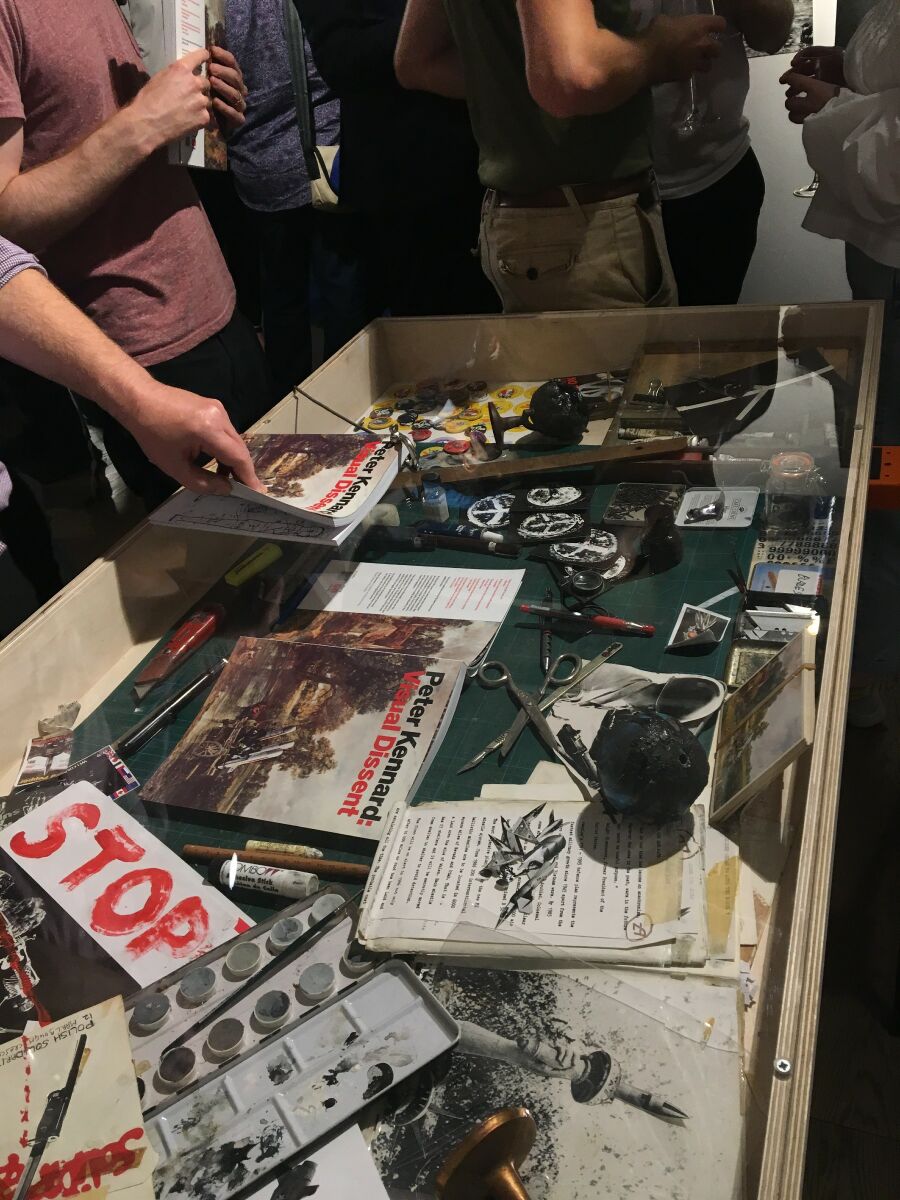 exhibition museum vitrine with selection of objects surrounded by people.